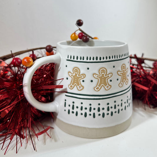 Gingerbread Man Mug, a white stoneware mug with gingerbread men and green dotted stripes, on red tinsel with a berry sprig