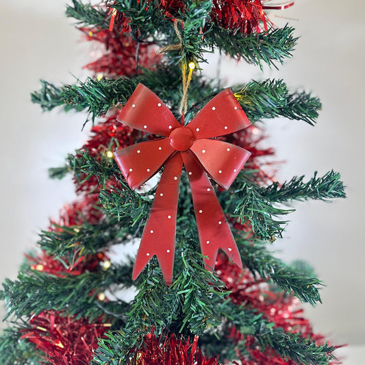 Red Polka Dot Bow Decoration with white dots hanging from twine on a Christmas tree with red tinsel
